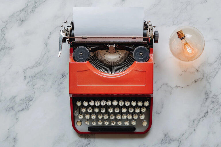 Vintage typewriter with blank paper on marble surface.